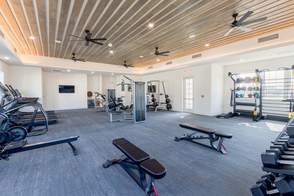 Et fitnesscenter med løbebånd, vægtbænke og håndvægte.