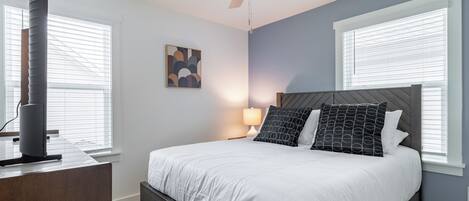 A bedroom with a bed, a ceiling fan, a bedside table, and a lamp.