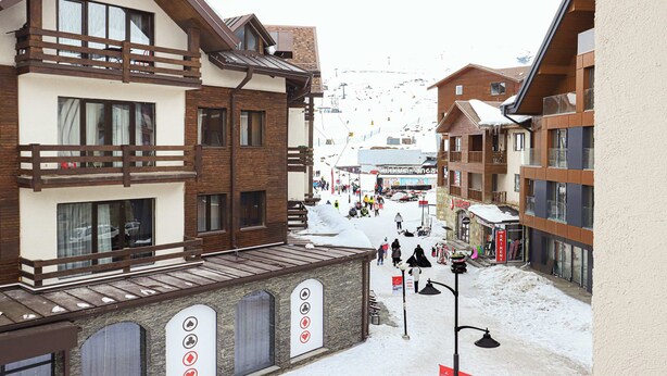 A snow-covered ski resort with multi-story buildings, a ski lift in the background, and a clear view of the slopes. - New Gudauri Redco Apt. | Comfort by Wehost (Gudauri)