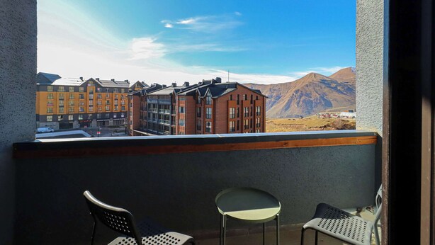 En balkon med to stole og udsigt til bygninger og bjerge.