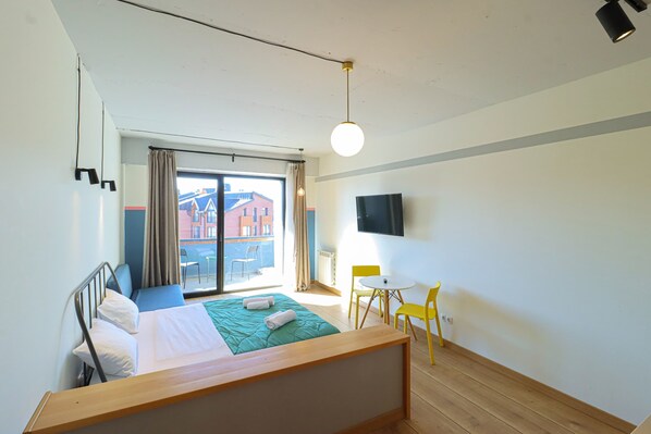 A hotel room with a bed, a TV, a window with curtains, a small table, and a chair. - Studio in Redco Gudauri Ski Paradise (Gudauri)
