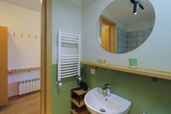 A bathroom with a white sink, a mirror, a towel rack, and a heater.