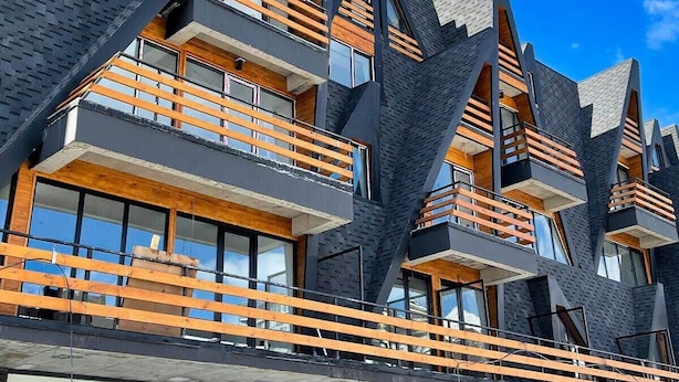 Een modern meerlaags gebouw met houten balkons en grote ramen.