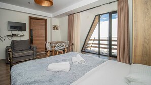 Een hotelkamer met een bed, een televisie, een bureau en uitzicht op de natuur.