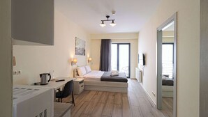 Una camera d'albergo compatta con un letto, un comodino, una scrivania, una sedia e un grande specchio.