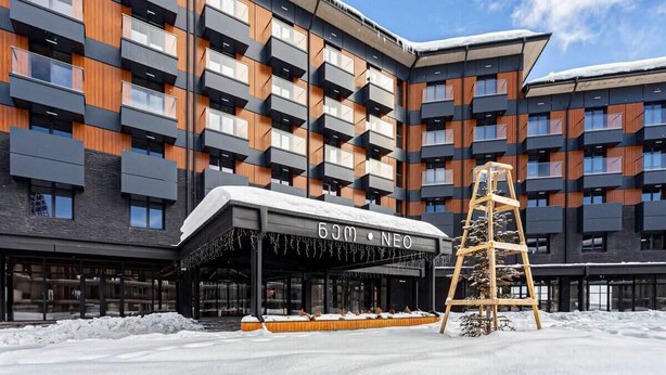 Un hotel moderno con un cartello NEO lungo 50 metri, diversi balconi e un'area d'ingresso coperta.