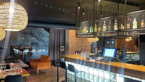 Ein moderner Barbereich mit Glastrennwand, Barhocker und einem Computermonitor.