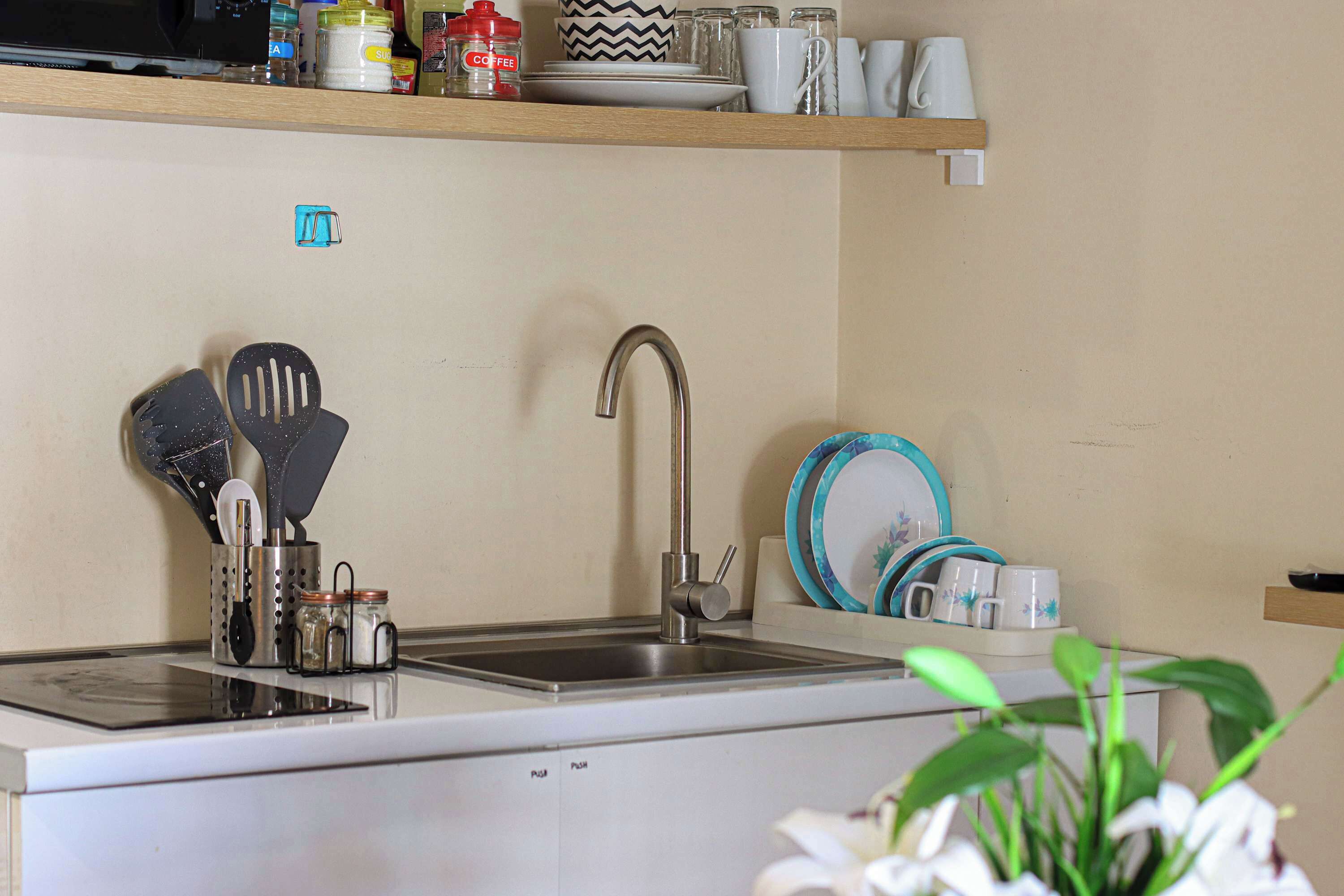 A kitchen with a stainless steel sink, a coffee maker, and various kitchen utensils.