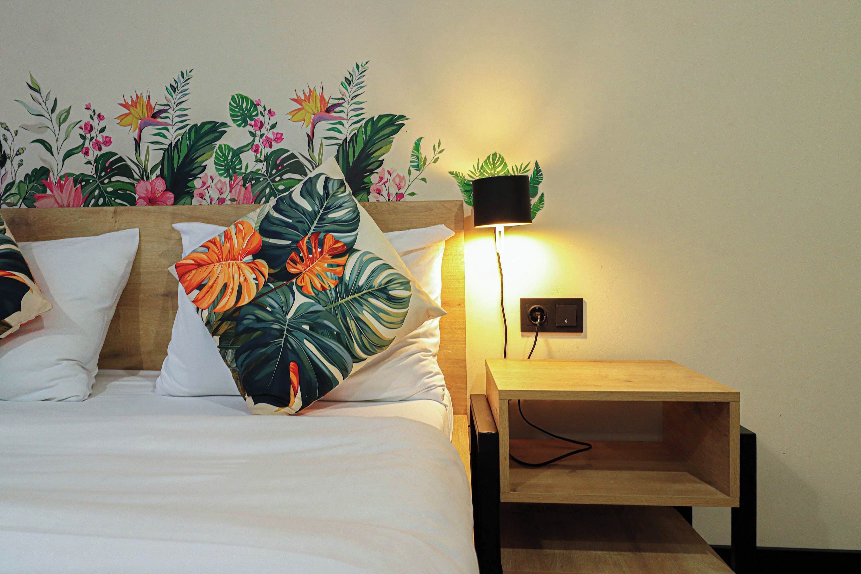 A bed with white bedding, a wooden headboard, and a nightstand with a lamp.