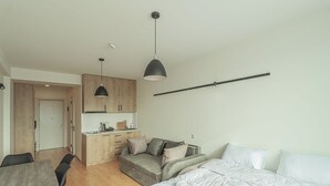 Un apartamento moderno y compacto con kitchenette, comedor y cama.