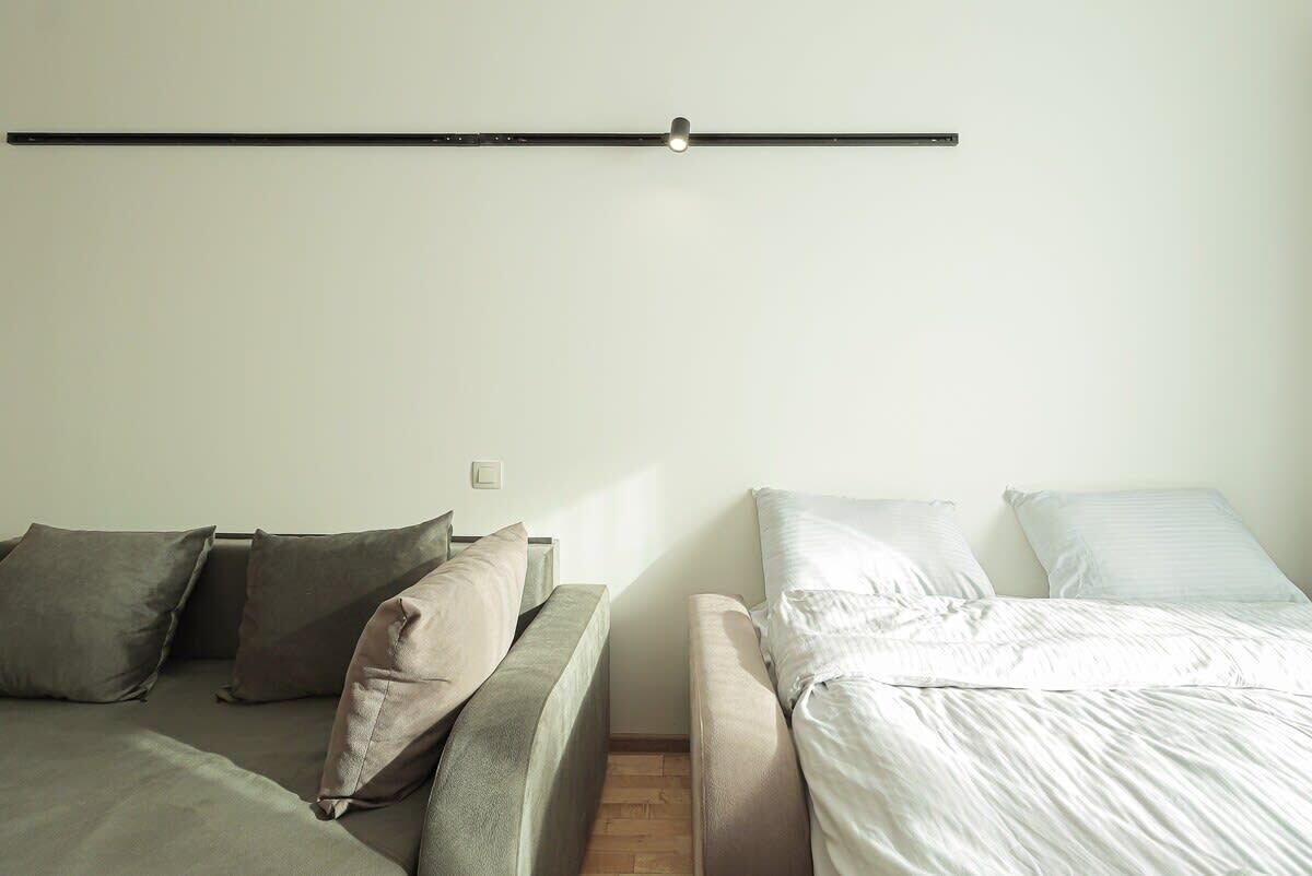 Une pièce comprenant un lit, un canapé et un luminaire fixé au mur.
