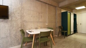 A conference room with a white table, green chairs, a mounted TV, and a door with a green panel. - Stylish Ski-In/Out Apt- Mountain Views - By Wehost (Gudauri)