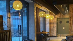 A modern interior with a wooden floor, a dining area with a table and chairs, and a seating area with sofas. - Cozy 1BR Ski Resort Apt in Gudauri - By Wehost (Gudauri)