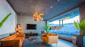 A modern interior with a sofa set, a TV, and a large window with a view of a snowy landscape. - Cozy 1BR Ski Resort Apt in Gudauri - By Wehost (Gudauri)
