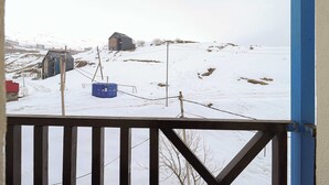 Un paysage enneigé avec une maison et un conteneur bleu sur une colline.