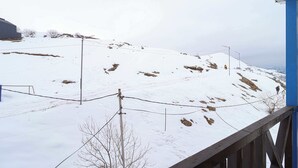 Un paysage enneigé avec une terrasse en bois et une structure de bâtiment bleue.