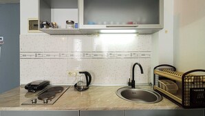 Une cuisine équipée d’une cuisinière, d’une machine à café, d’un évier et d’un égouttoir à vaisselle.