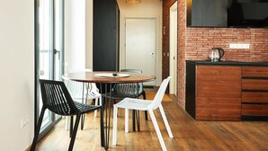 A modern kitchen with a brick wall, wooden cabinets, and a dining area with a round table and chairs. - New Gudauri Studio with Balcony By Wehost (Gudauri)