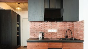 A modern kitchen with a brick backsplash, a black countertop, and wooden cabinets. - New Gudauri Studio with Balcony By Wehost (Gudauri)