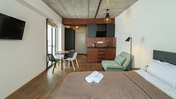 A modern hotel room with a large bed, a dining area, and a kitchenette. - New Gudauri Studio with Balcony By Wehost (Gudauri)