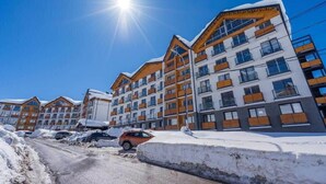 A multi-story hotel with balconies and a snow-covered ground. - New Gudauri Studio with Balcony By Wehost (Gudauri)