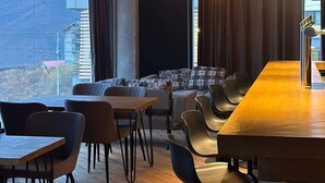 A modern dining area with a long wooden table, several chairs, and hanging spherical light fixtures. - Gudauri Cozy Studio - Adventure Ready - By Wehost (Gudauri)