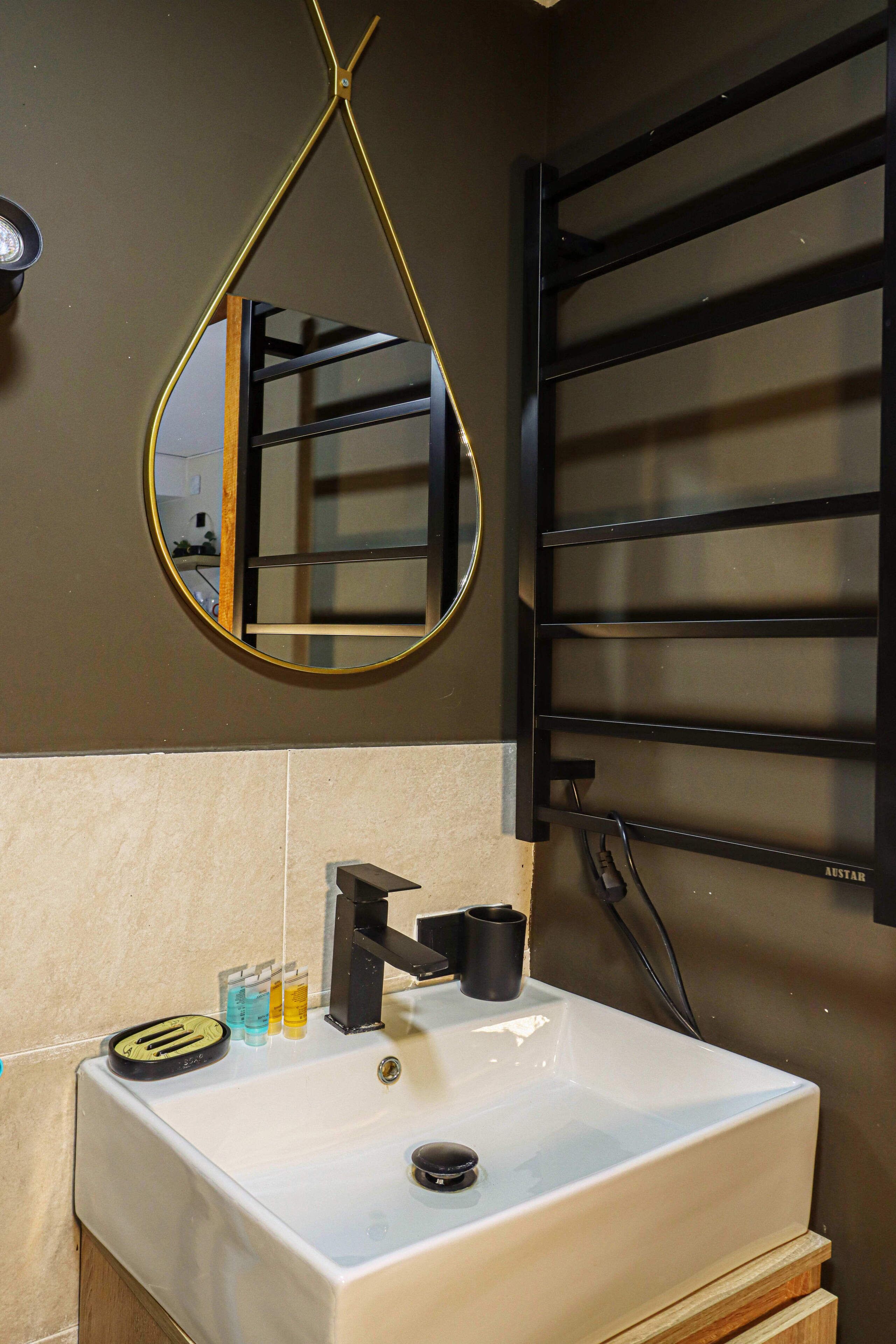 Une salle de bain avec un lavabo blanc, un miroir et un porte-serviettes.
