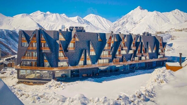 A modern building with a unique geometric design, surrounded by snow-covered mountains. - Charming studio In Marshall Gudauri -By Wehost (Gudauri)