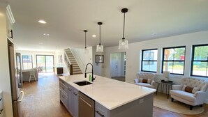 Un'ampia cucina con isola centrale, un'area pranzo con divano e una scala che conduce a un piano superiore.