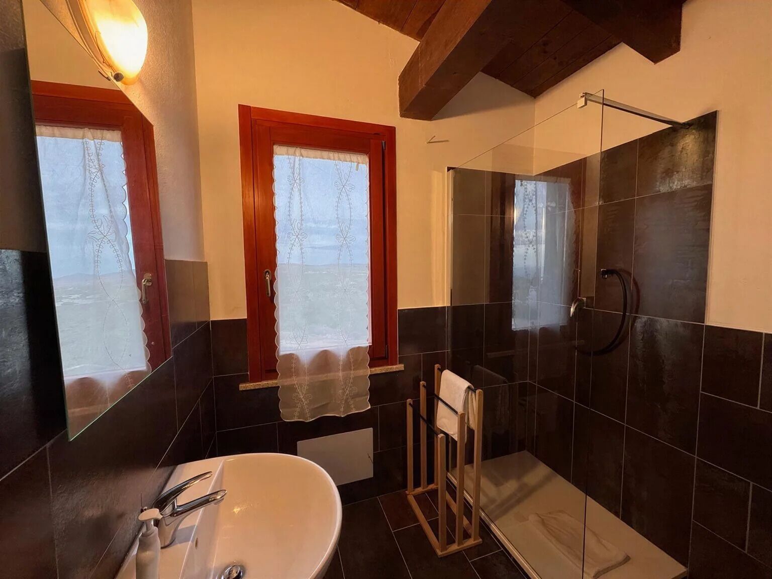 A bathroom with a white sink, a glass shower enclosure, and a wooden door.