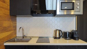 Una cocina moderna con un lavamanos de acero inoxidable, un hervidor, un tostador y un microondas.