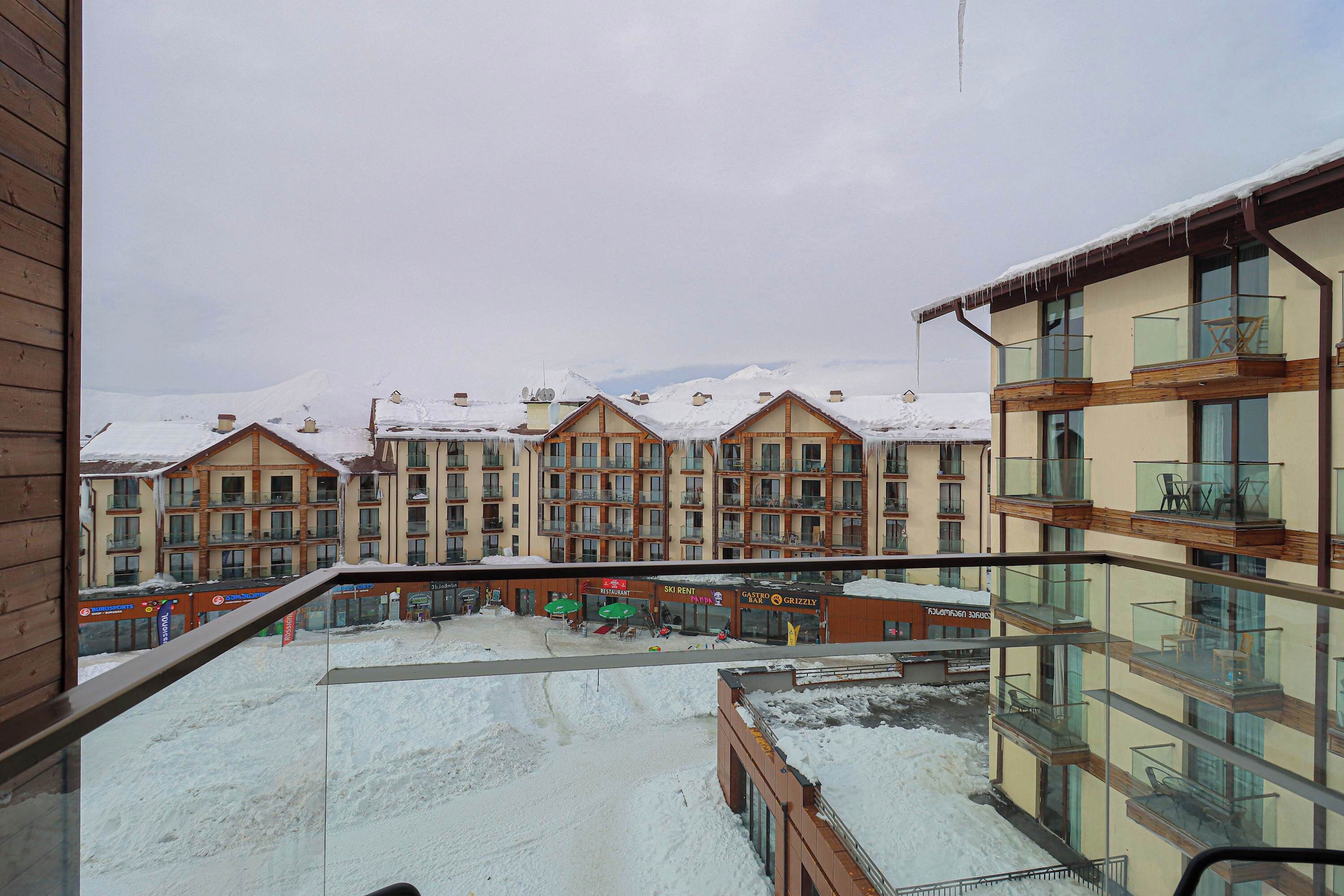 A hotel with multiple balconies, a ski rental sign, and snow-covered surroundings.