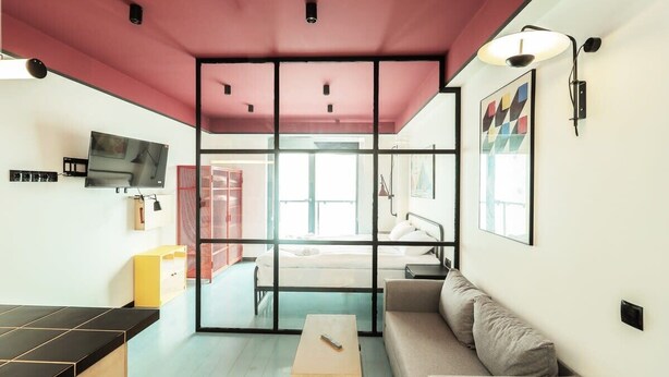 A modern room with a large window, a sofa, a small table, and a television. - Super Stylish Apartment In New Gudauri -By Wehost (Gudauri)