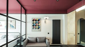 A modern hotel room with a bed, a sofa, a small table, a radiator, and a large window. - Super Stylish Apartment In New Gudauri -By Wehost (Gudauri)