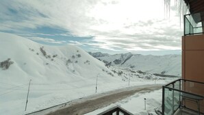 A snowy mountain landscape with a road and a building with a glass balcony. - Super Stylish Apartment In New Gudauri -By Wehost (Gudauri)