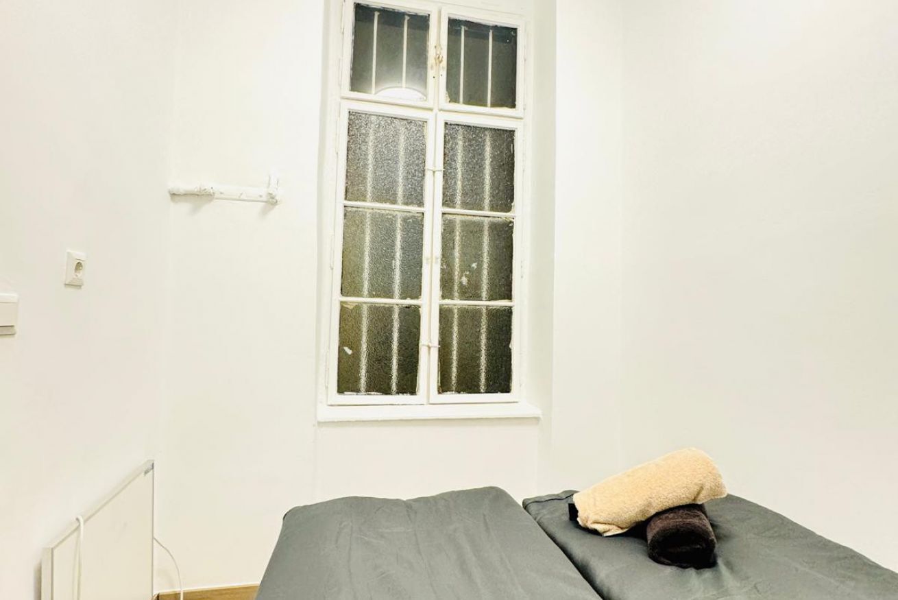 Un lit simple avec un matelas gris et une serviette enroulée.