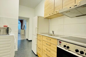 Eine Küche mit weißen Schränken, einem Edelstahlherd und einem Kühlschrank.