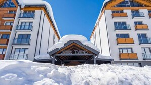 En hotelindgang med et skilt der siger "0806 Twins" og et tag dækket af sne.