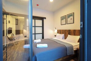 Une chambre d’hôtel avec un lit, un bureau et une chaise. Deux tableaux encadrés sont accrochés au mur.