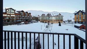 A snow-covered hotel with multiple buildings, a parking lot, and a ski lift in the background. - Brand New Ski 1BR Apt In New Gudauri - By Wehost (Gudauri)