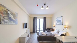 Une chambre d’hôtel équipée d’un lit, d’un bureau, d’une télévision et décorée avec des œuvres d’art.