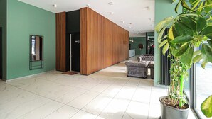 Un hall d’entrée spacieux avec un séparateur en bois, un comptoir d’accueil et un espace détente.