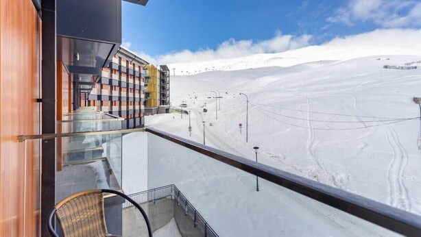 Un balcon donnant sur un paysage enneigé et un bâtiment aux façades colorées.