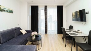 Una sala moderna con un sofá, una mesita redonda y una mesa de comedor con sillas.