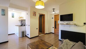 Ein modernes Wohnzimmer mit einem Couchtisch aus Holz, einem grauen Sofa und einem an der Wand befestigten Fernseher.