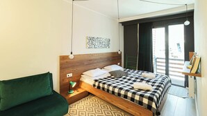 A modern bedroom with a wooden headboard, a checkered bedspread, a green sofa, and a patterned rug. - Modern Mountain Retreat in Gudauri – By Wehost (Gudauri)
