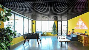 A modern indoor space with a foosball table, a small Christmas tree, and a bright yellow wall. - Modern Mountain Retreat in Gudauri – By Wehost (Gudauri)