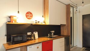 A modern kitchen with a microwave, toaster, and red dishwasher. - Modern Mountain Retreat in Gudauri – By Wehost (Gudauri)