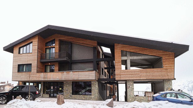 A modern multi-story building with a wooden facade and balconies. - Cozy & Family-friendly Apt. in Gudauri - by Wehost (Gudauri)