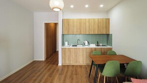 A modern kitchen with wooden cabinets, a green-tiled backsplash, and a wooden dining table with green chairs. - Cozy & Family-friendly Apt. in Gudauri - by Wehost (Gudauri)